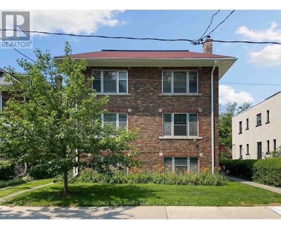A red brick house with a tree in front.