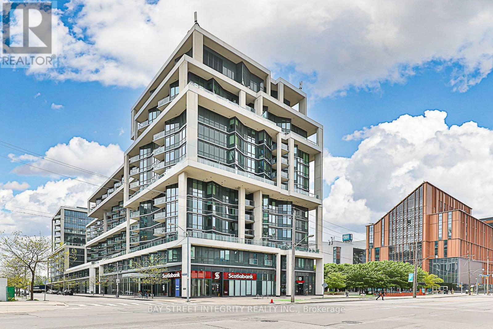 A modern multi-story building with glass windows and a red awning at the entrance.