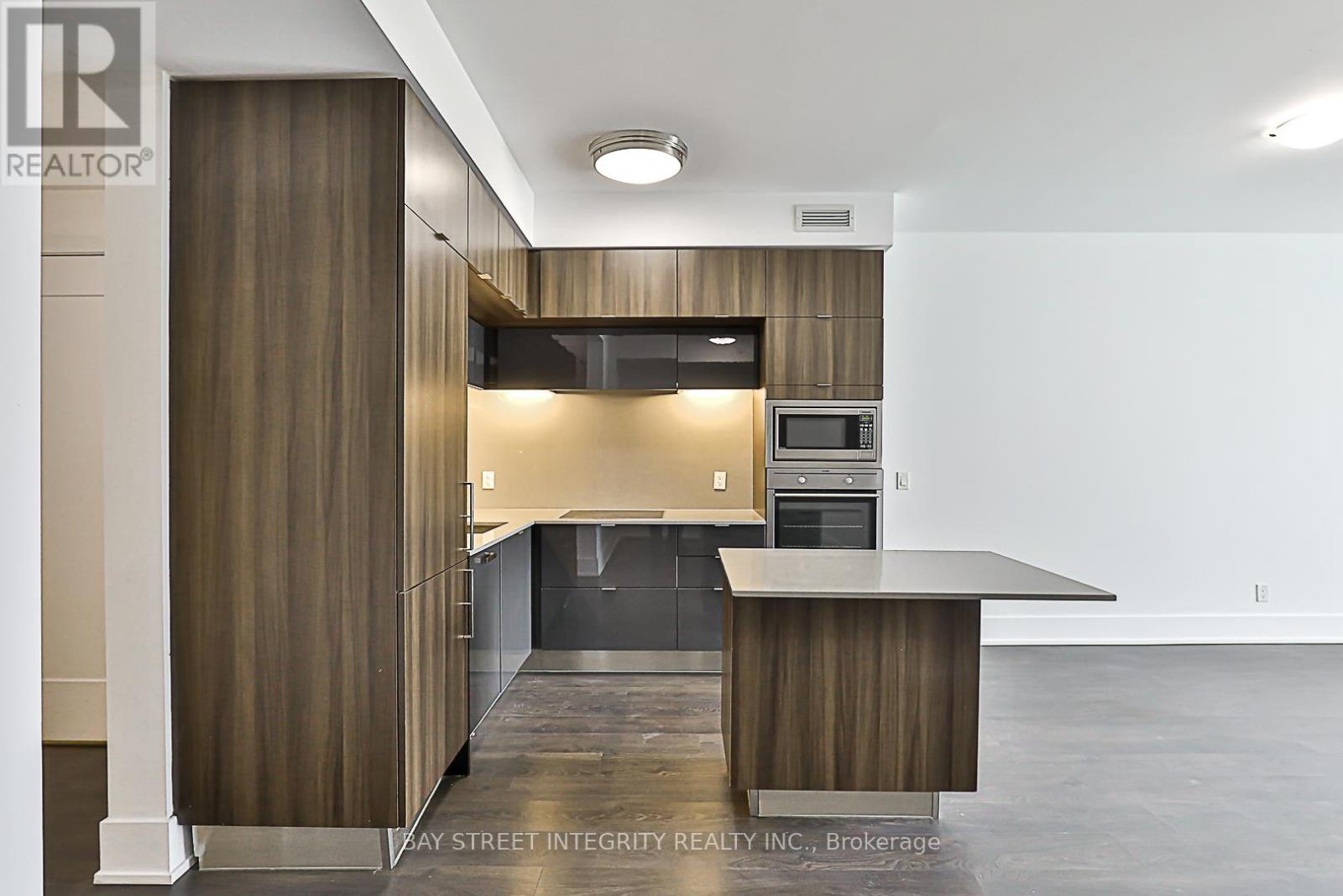 A modern kitchen with a large island and a refrigerator.