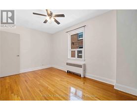 A room with a ceiling fan and a window with a view of a brick building outside.