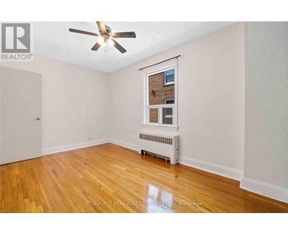 A room with a ceiling fan and a window with a view of a brick building outside.