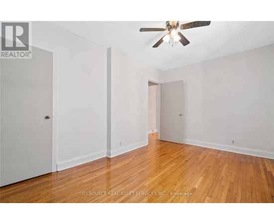 A room with a ceiling fan and wooden floors.