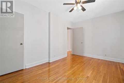 A room with a ceiling fan and wooden floors.