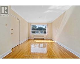 A room with wooden floors and a window overlooking a tree.