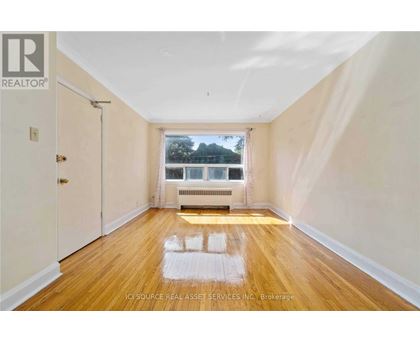 A room with wooden floors and a window overlooking a tree.
