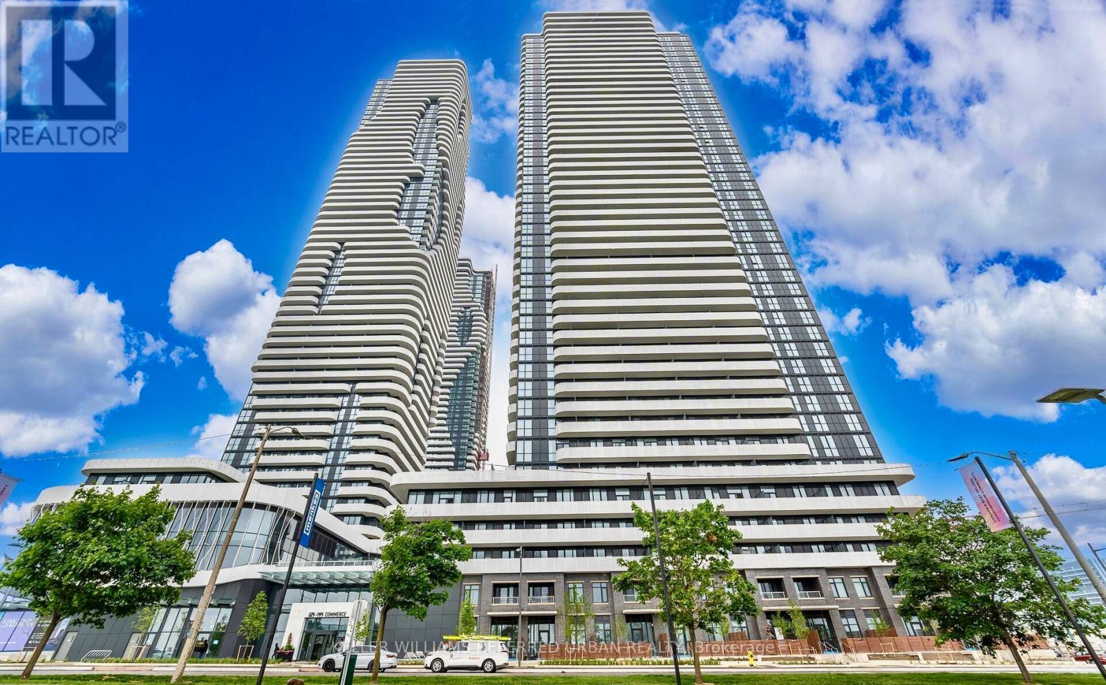 A modern building with a glass facade stands tall against a blue sky.