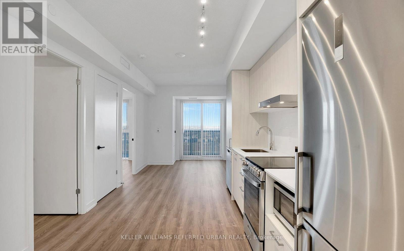 A modern kitchen with stainless steel appliances and wooden flooring.