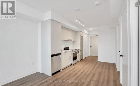 A spacious kitchen with white cabinets and a wooden floor.