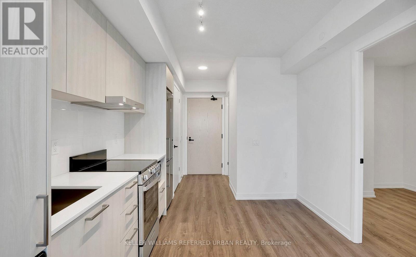 A spacious kitchen with white cabinets and a wooden floor.