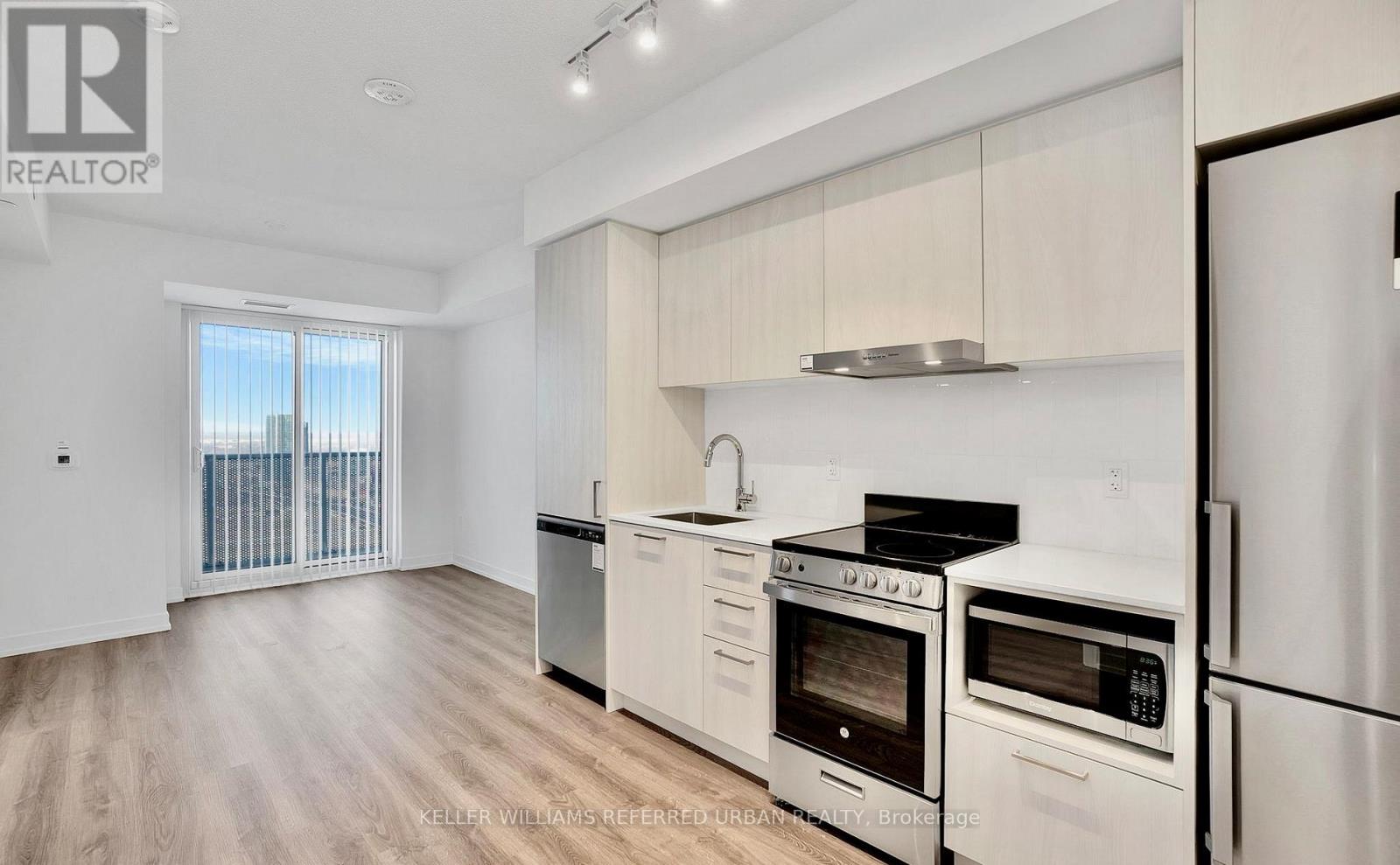A modern kitchen with white appliances and wooden floors.