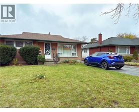 A blue car is parked in front of a house with a sign that says REALTOR.