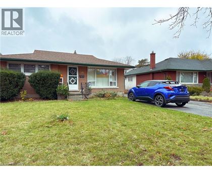A blue car is parked in front of a house with a sign that says REALTOR.