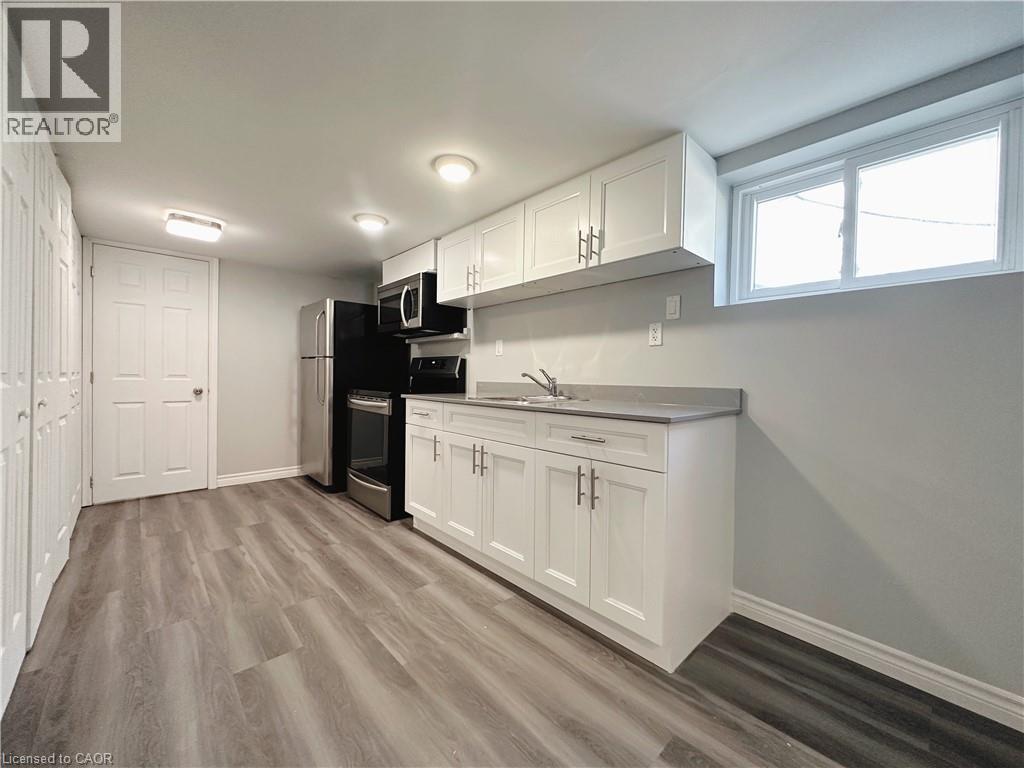 A kitchen with white cabinets and a wooden floor.