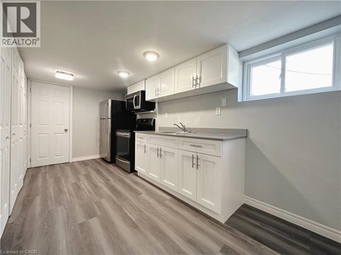 A kitchen with white cabinets and a wooden floor.