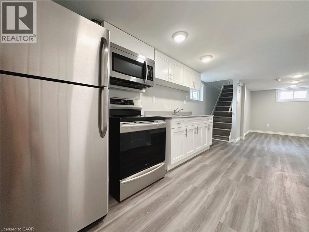 A modern kitchen with a stainless steel refrigerator and wooden flooring.