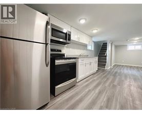 A modern kitchen with a stainless steel refrigerator and wooden flooring.