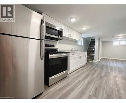 A modern kitchen with a stainless steel refrigerator and wooden flooring.
