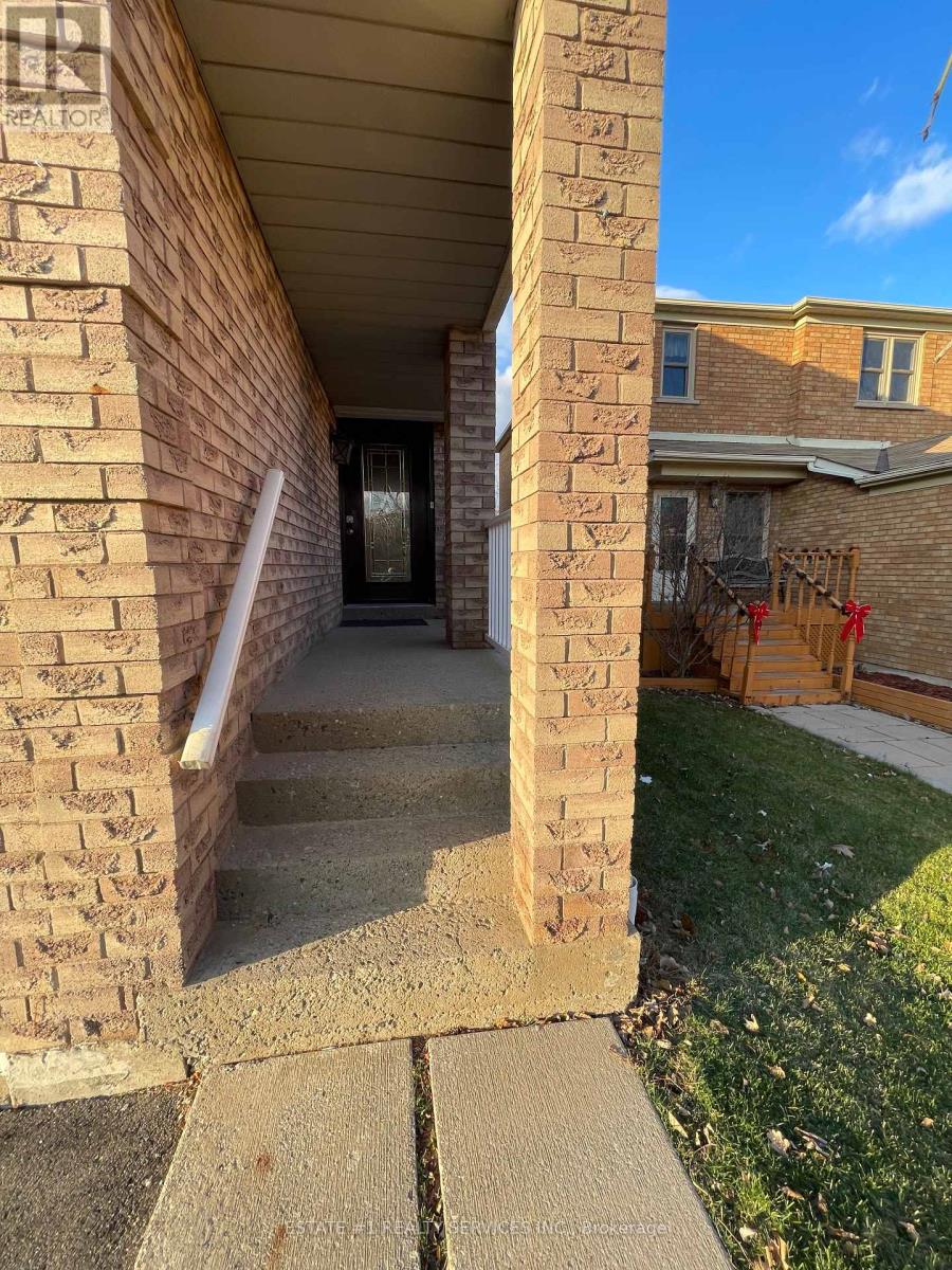 A house entrance with a brick pillar and a concrete walkway.