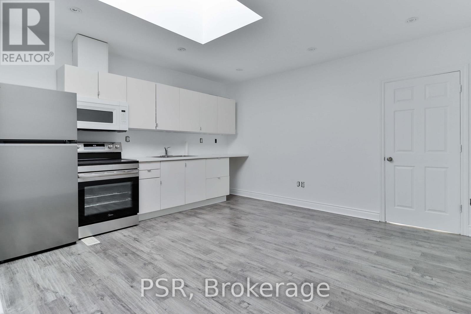 A spacious kitchen with white cabinets and a stainless steel refrigerator.