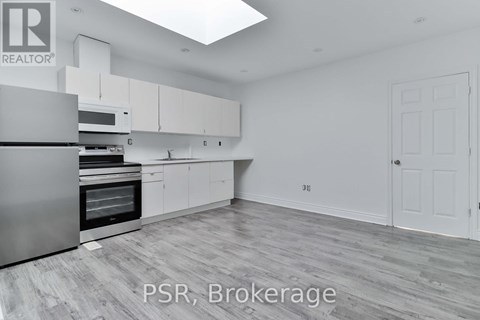 A spacious kitchen with white cabinets and a stainless steel refrigerator.