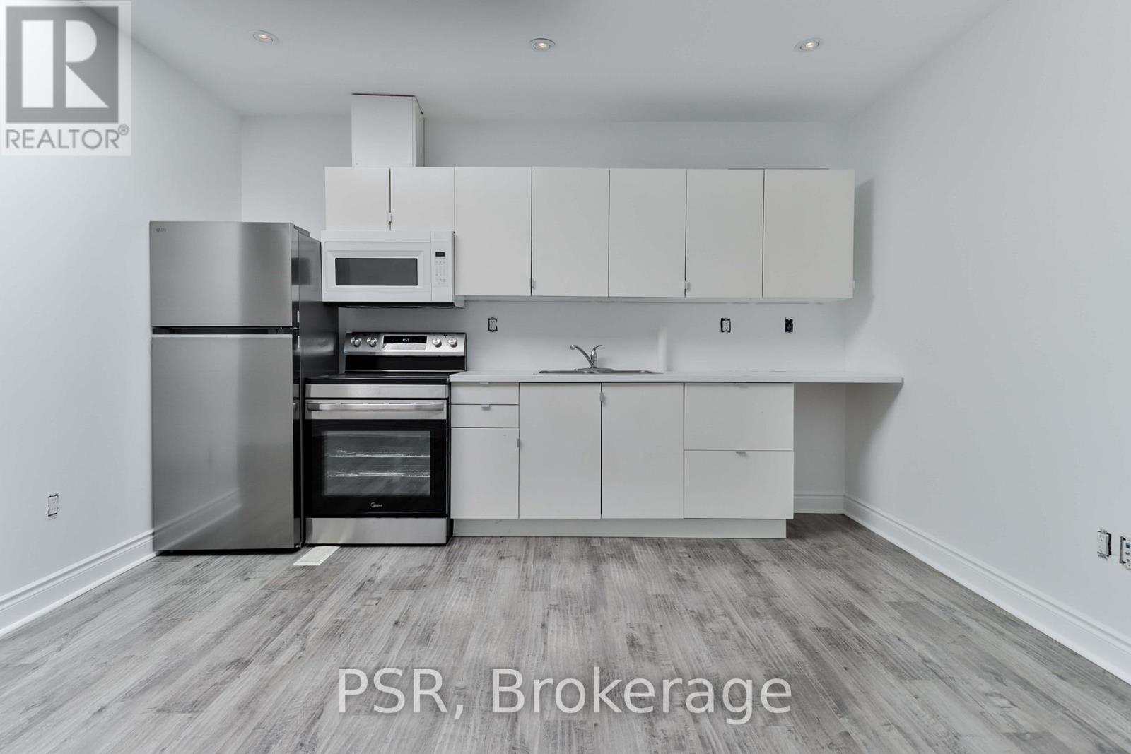A kitchen with a refrigerator, oven, and microwave.