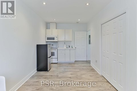 A kitchen with white cabinets and a black trash can.
