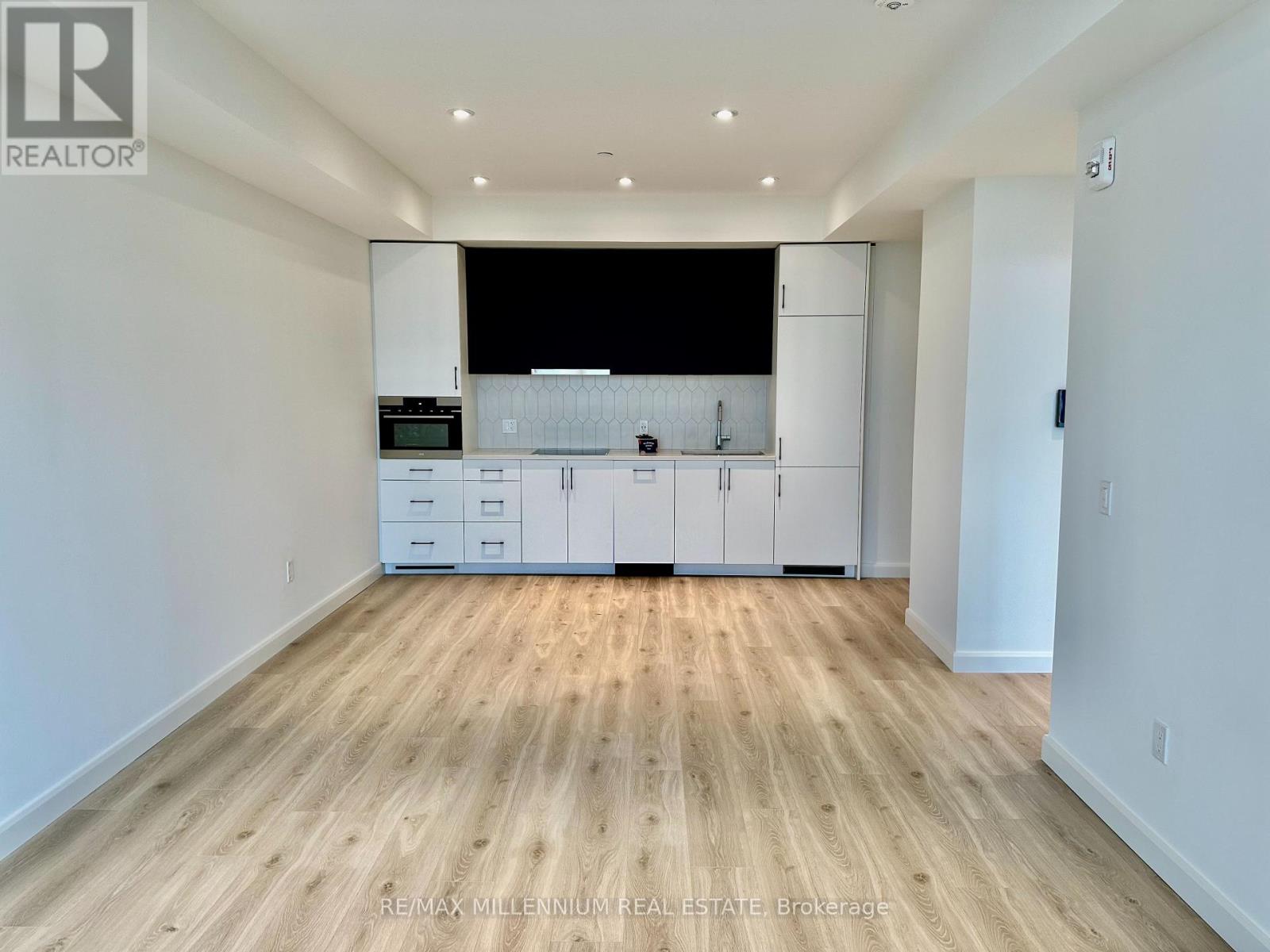 A spacious kitchen with white cabinets and a wooden floor.