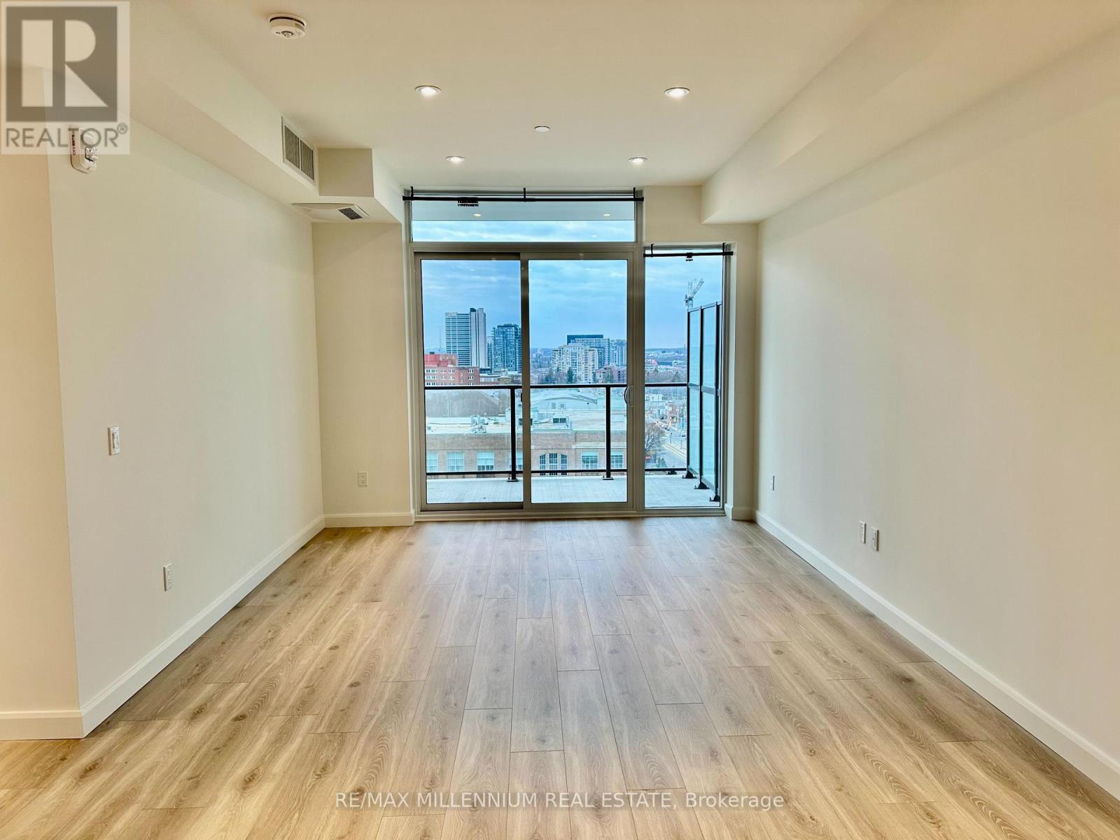 A spacious room with wooden floors and a view of the city through large windows.