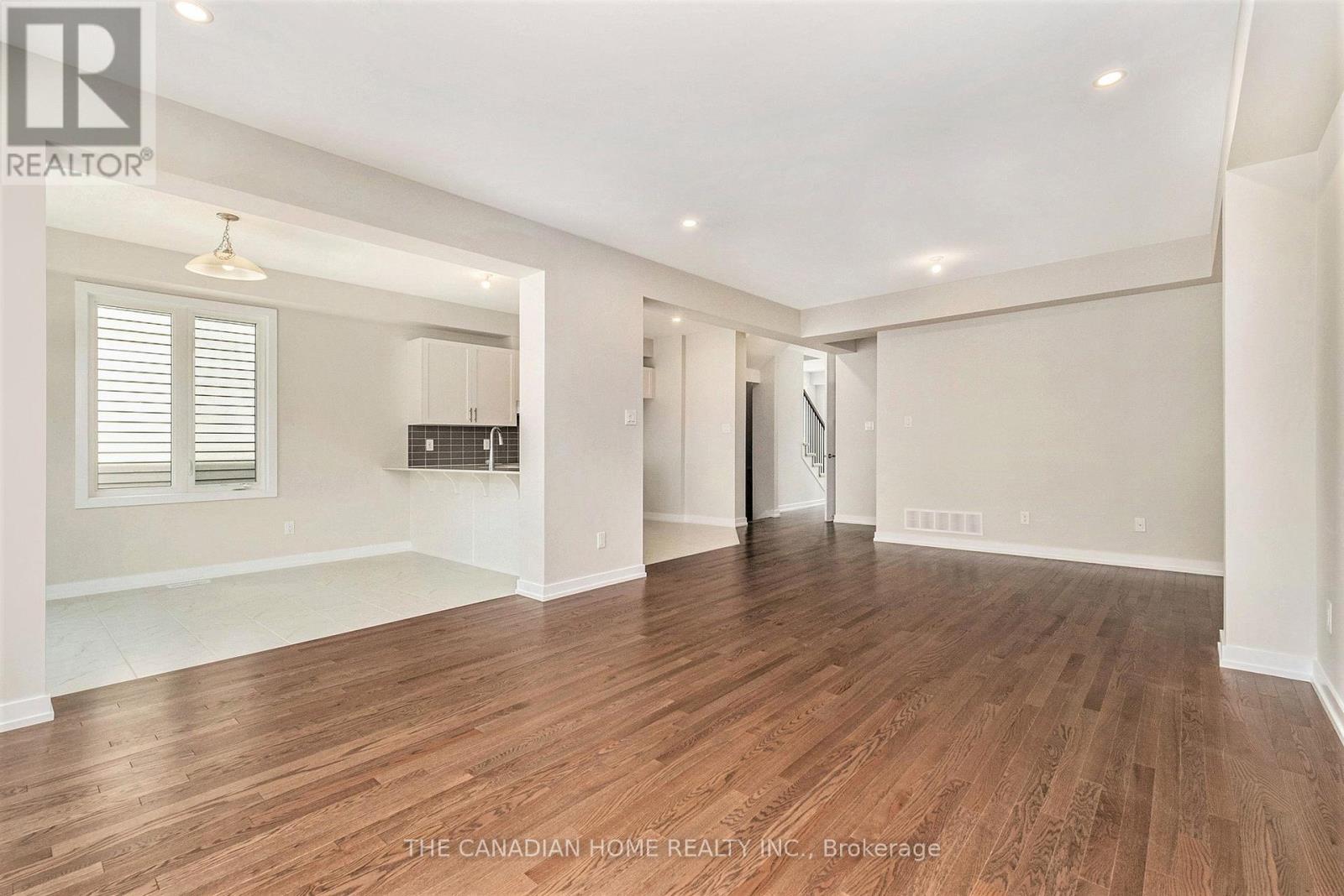A spacious room with wooden flooring and white walls.
