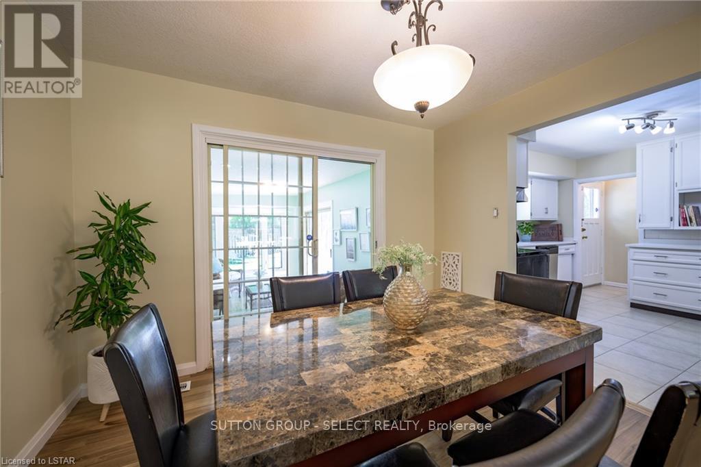 A dining room with a table and chairs and a plant.