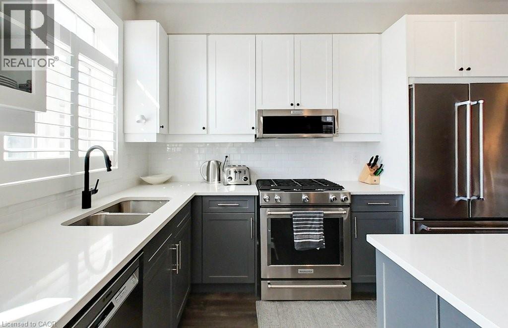 A modern kitchen with a stainless steel refrigerator and a black oven.