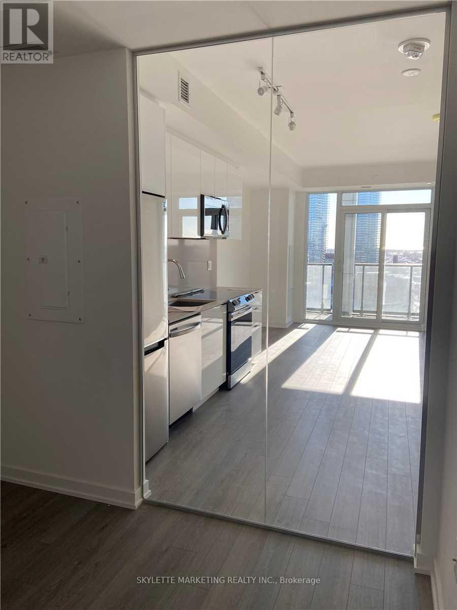 A modern kitchen with white cabinets and a glass door leading to a balcony.