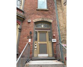 A brown door with a window above it and a metal railing on the left.