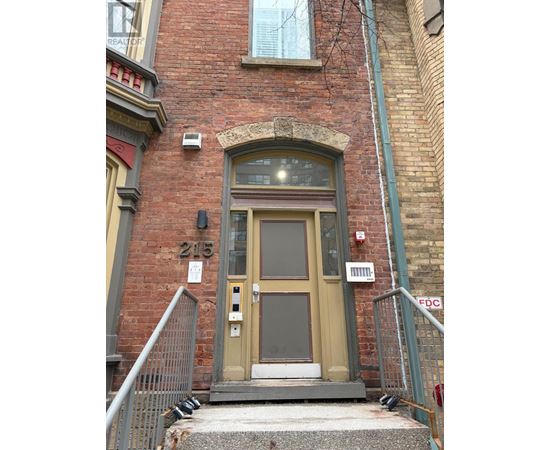 A brown door with a window above it and a metal railing on the left.