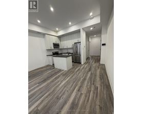 A modern kitchen with wood flooring and white walls.