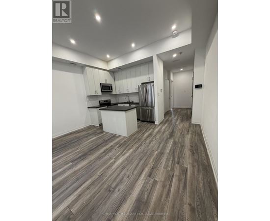 A modern kitchen with wood flooring and white walls.
