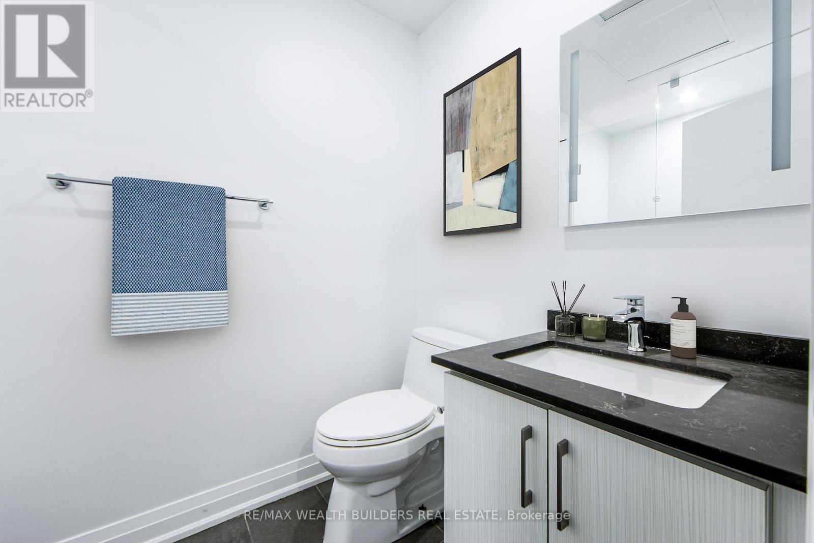 A bathroom with a toilet, sink, and a mirror.