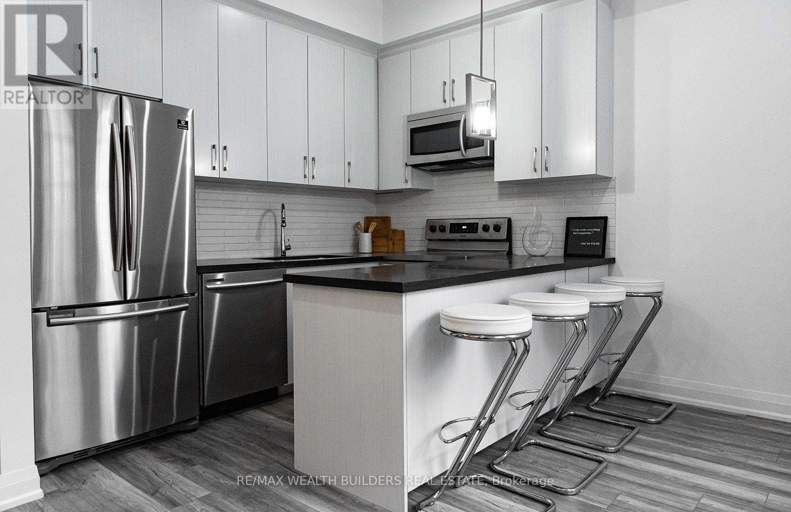 A modern kitchen with a stainless steel refrigerator and white cabinets.
