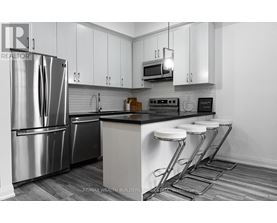 A modern kitchen with a stainless steel refrigerator and white cabinets.
