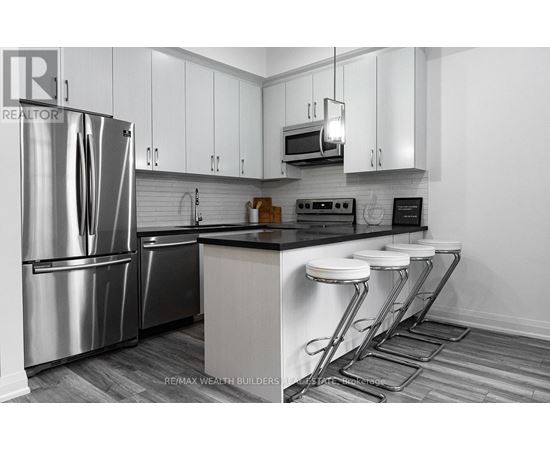 A modern kitchen with a stainless steel refrigerator and white cabinets.