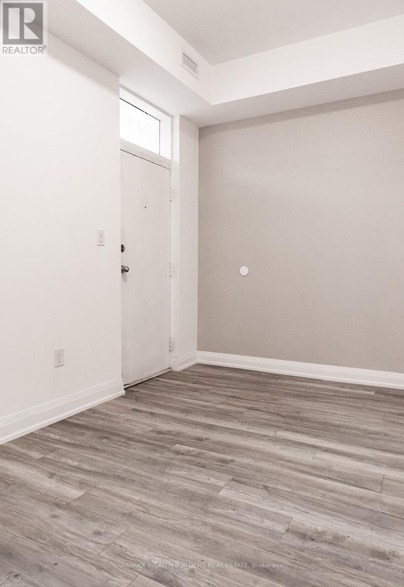 A room with a white door and a wooden floor.