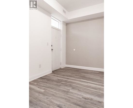 A room with a white door and a wooden floor.