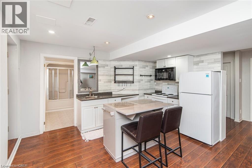 A modern kitchen with white appliances and a wooden floor.