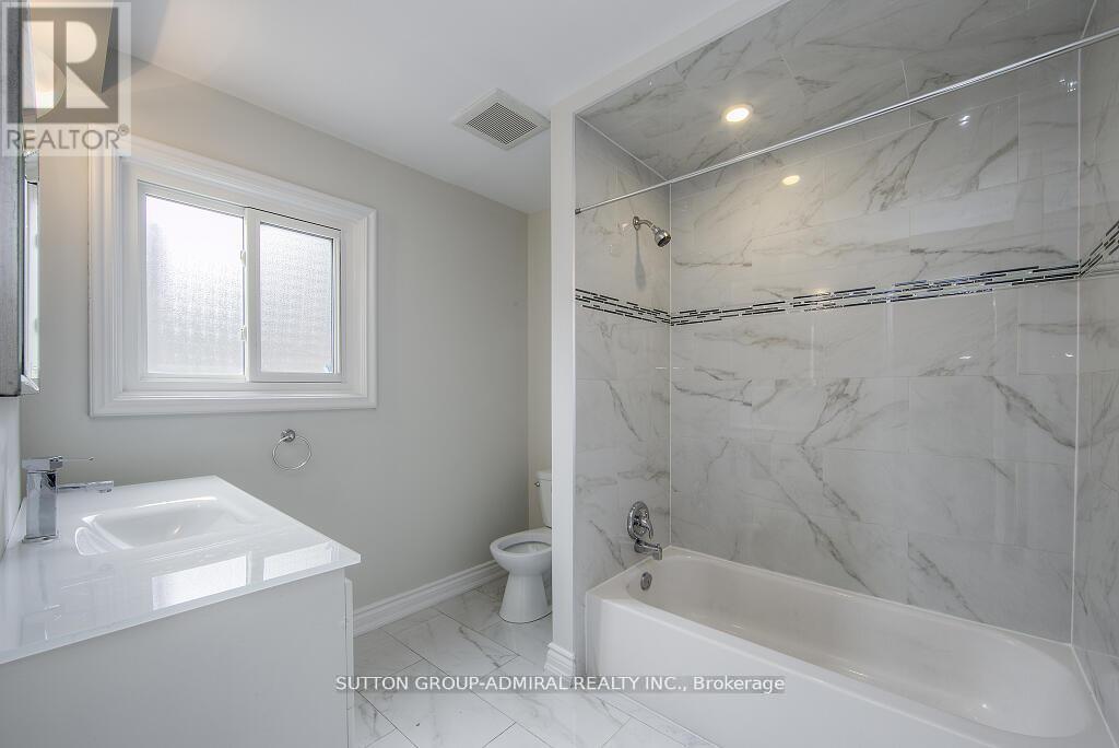 A white bathroom with marble tiles on the walls and floor.