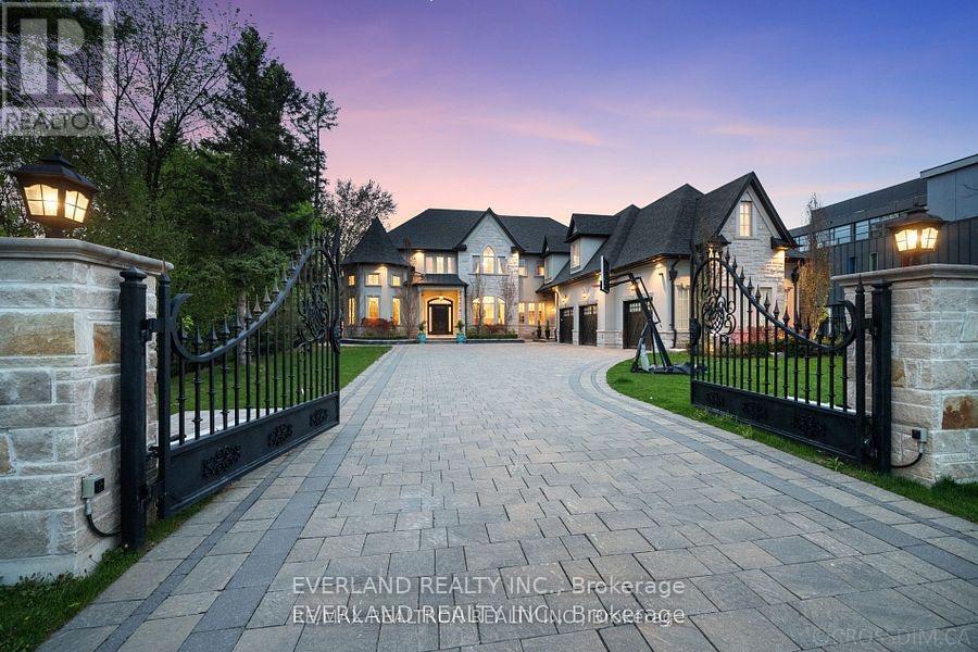 A gated entrance to a large, luxurious house with a stone pathway leading to the gates.