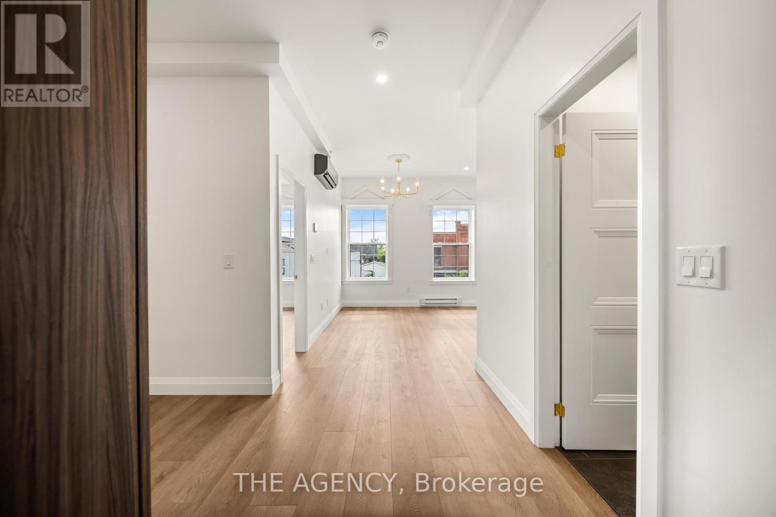 A hallway with a wooden floor and white walls leading to a door.