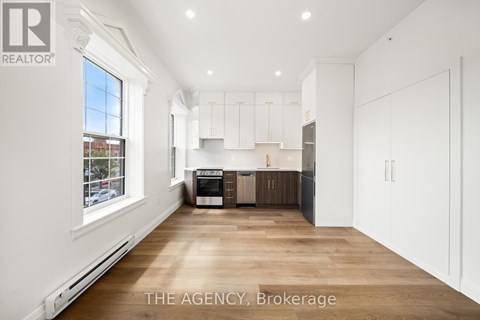 A spacious kitchen with white cabinets and a wooden floor.