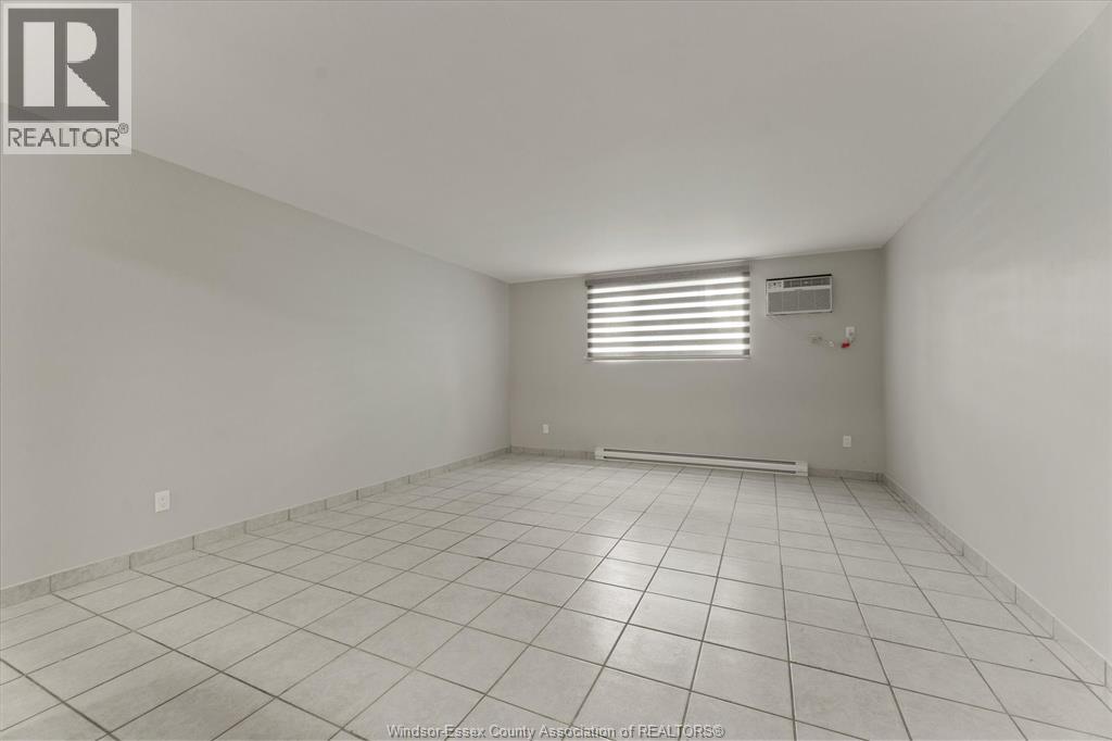 A spacious empty room with tiled flooring and white walls.