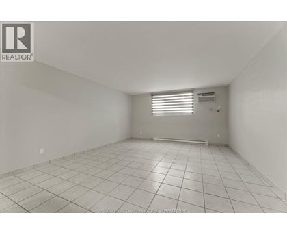 A spacious empty room with tiled flooring and white walls.