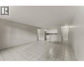 A spacious empty room with tiled flooring and white walls.
